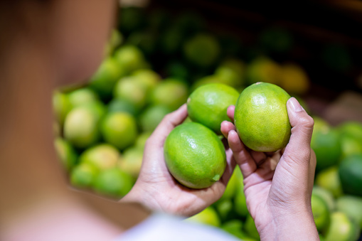 Close-up on a woman picking-up limes at the supermarket while shopping for groceries