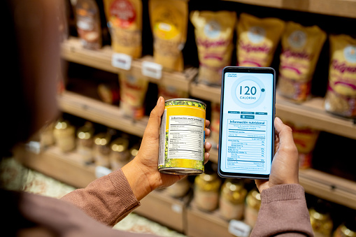 Close-up on a woman scanning the nutrition label on a can at the supermarket while counting calories - healthy eating concepts