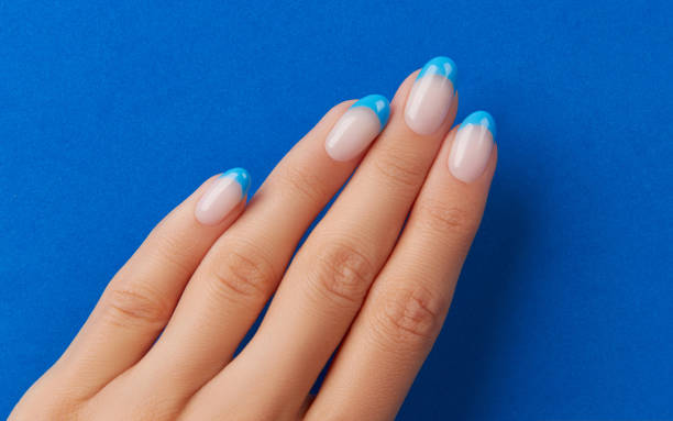 istock Beautiful womans hand trendy nail design on blue background. 1562969099