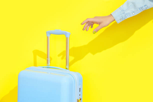istock Blue suitcase on a yellow background with long deep shadows. Travel concept 1562969964