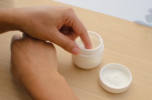 Close-up of hands spreading a moisturizing cream to promote healthy, nourished skin.