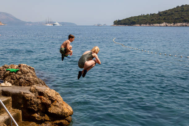 Two children jumping into the sea. stock photo