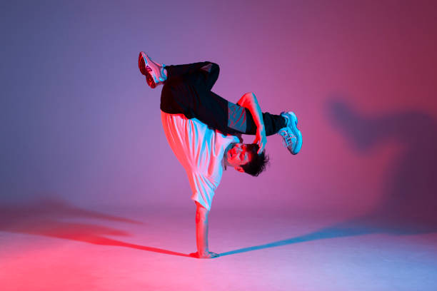 istock young guy dancer is dancing break in neon lighting, male acrobat is doing trick and dance exercise 1562972622