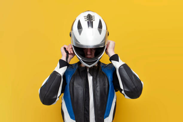 istock young guy motorcyclist in leather jacket puts on helmet on yellow isolated background 1562972736