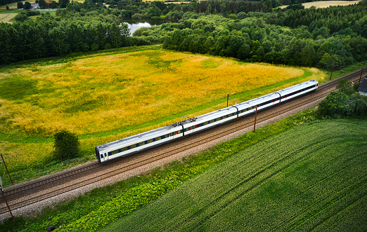 Gray train on railway high angle view passing agricultural green fields