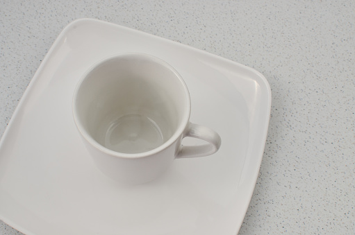 Closeup of a high quality porcelain cup on top of a white plate, ready to be filled.