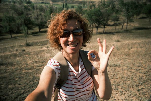 istock Cheerful 45-year old female backpacker is laughing while making selfie of her travelling 1562976445