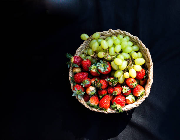 Wicker basket with strawberries and fresh grapes.