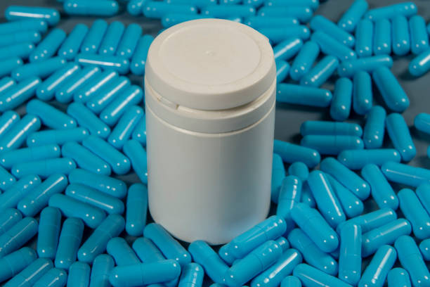 istock Blue antibiotic capsule pills texture with white bottle. Pharmaceutical production. Global health. Resistance to antibiotic drugs. Gelatin capsule pills 1563005766