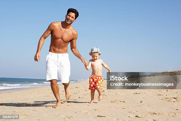 Pai E Filho De Corrida Ao Longo Da Praia - Fotografias de stock e mais imagens de Calções de Praia - Calções de Praia, Calções, Criança