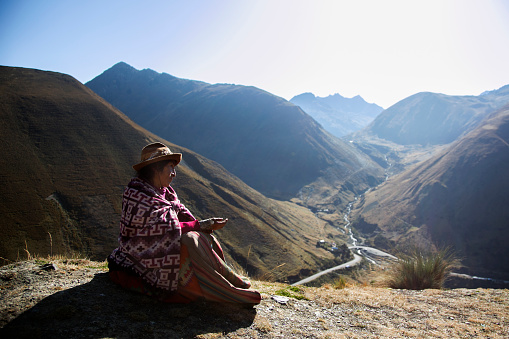 A woman from a Quechua tribe sitting with the sacred valley in the background.