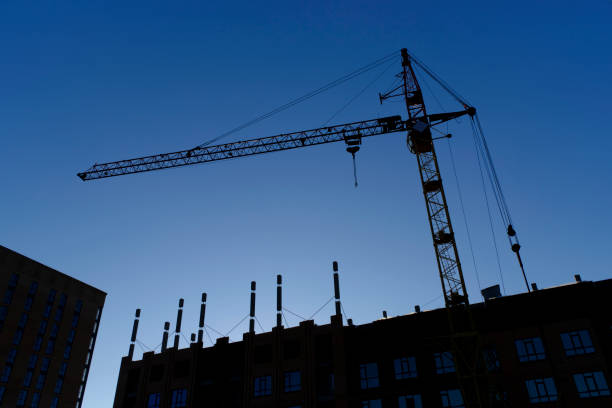 istock Silhouette high rise crane and building under construction against blue sky. 1563031755