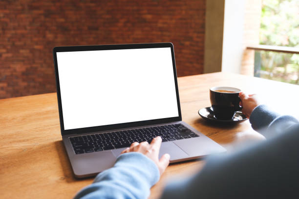 istock Mockup image of a woman using and working on laptop computer with blank white desktop screen while drinking coffee 1563032827