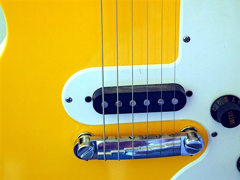 Close-up showing the pickup selector switch and volume control on a vintage style electric guitar, with the guitar's strings, pickguard, bridge and pickups visible in the background.