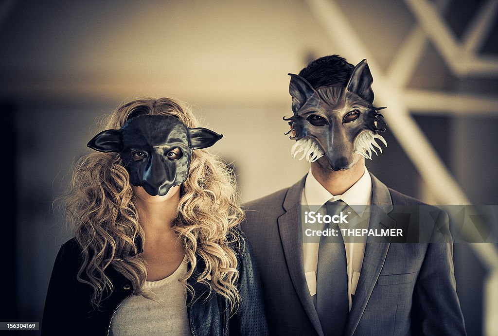 young couple wearing animal mask young couple with animal mask (male as wolf - female as a sheep) wearing business like attire posing against a light shaded background Wolf Stock Photo