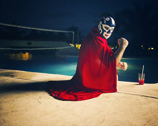 mexican luchador by the pool mexican luchador by the pool with a red drink looking angry at camera face guard sport photos stock pictures, royalty-free photos & images