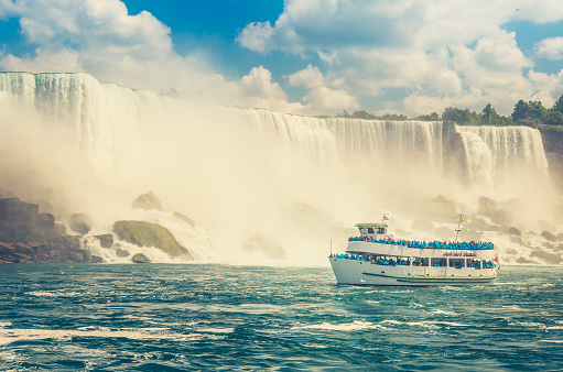 tourist boat passes in front of the American Falls on USA side, shoot from Canadian side