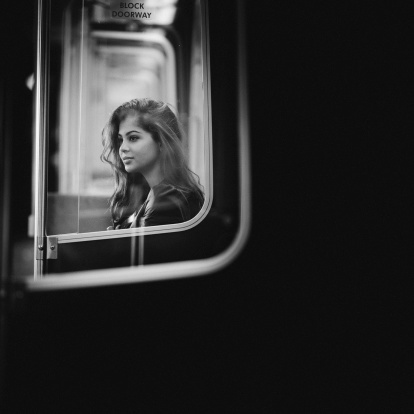 thoughtful woman on a empty subway wagon, shoot thru two pieces of glass.
