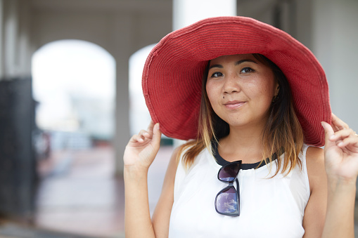 Close up portrait of a young Kazakh lady with huge red hat enjoying Istanbul vacation