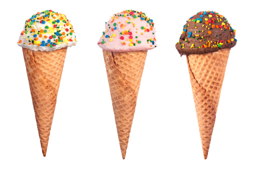 An assortment of waffle cone ice cream with chocolate, strawberry and vanilla ice cream scoops coverd with colorful candy sprinkled.