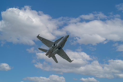 F-18 Super Hornet fighter jet in the air against a blue sky and clouds