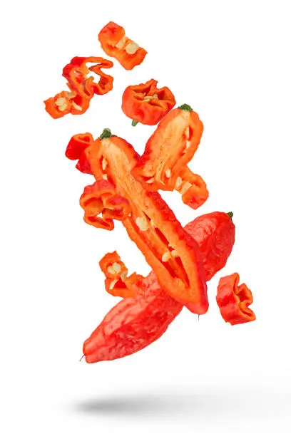 Photo of Flying pepper. Pods of fresh habanero peppers fly in different directions on a white isolated background. Different parts of the habanero pepper along and across on a white background. Close-up.