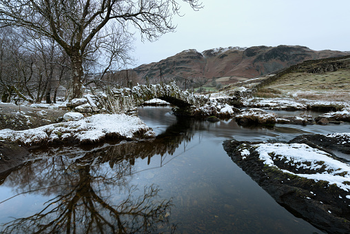 Old packhorse bridge known as ‘Slaters Bridge’ crossing the River Brathay near Little Langdale taken on a fresh Winter morning with a dusting of snow.