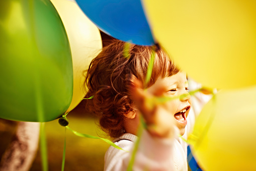 Happy little boy has fun between colorful balloons.Outdoors shot.