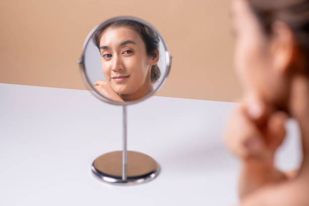 istock Attractive young Asian woman looking at herself in the mirror, checking her complexion 1563168330
