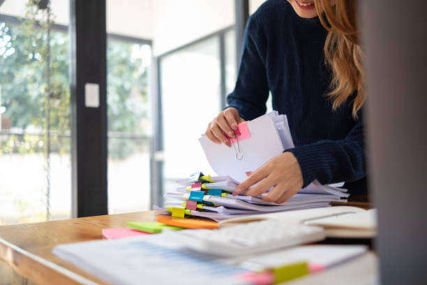 istock secretary searches through stacked documents on desk in office to find lease within stacked documents just before meeting. concept difficulty in finding hire purchase contract from stacked documents 1563199915
