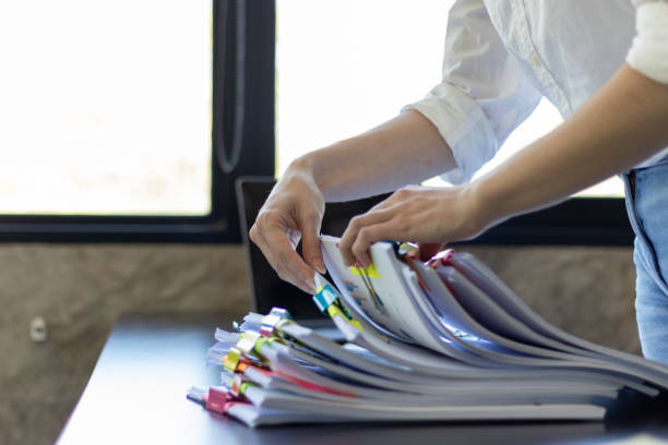 istock secretary searches through stacked documents on desk in office to find lease within stacked documents just before meeting. concept difficulty in finding hire purchase contract from stacked documents 1563200481