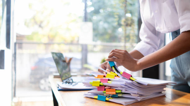 istock secretary searches through stacked documents on desk in office to find lease within stacked documents just before meeting. concept difficulty in finding hire purchase contract from stacked documents 1563200488