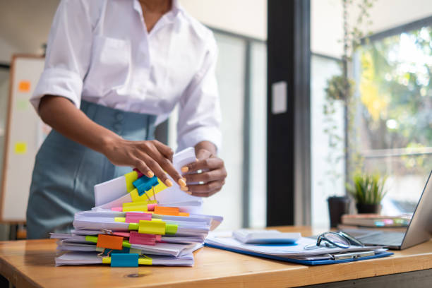 istock secretary searches through stacked documents on desk in office to find lease within stacked documents just before meeting. concept difficulty in finding hire purchase contract from stacked documents 1563201001