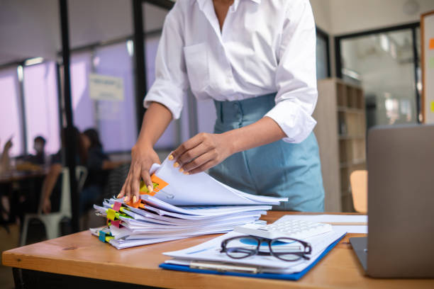 istock secretary searches through stacked paperwork on desk in office to find lease within stacked paperwork just before meeting. concept difficulty in finding hire purchase contract from stacked paperwork 1563201005
