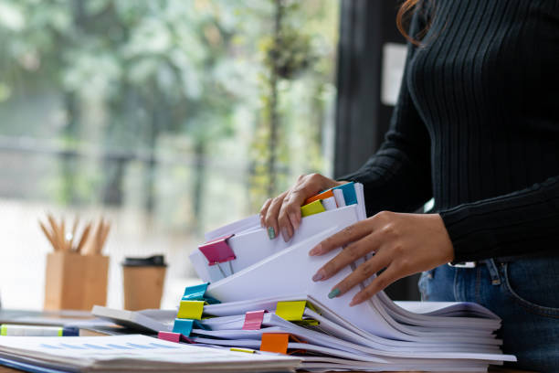 istock secretary searches through stacked documents on desk in office to find lease within stacked documents just before meeting. concept difficulty in finding hire purchase contract from stacked documents 1563201544
