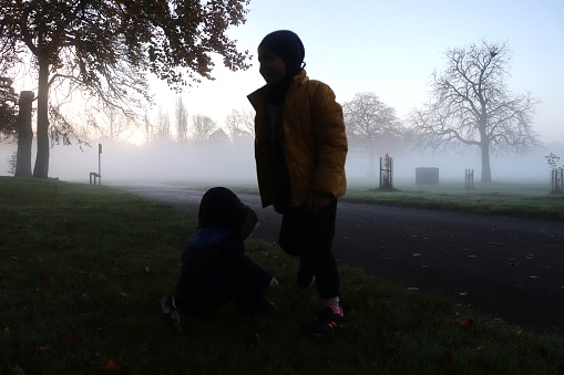 Silhouette of kids playing in the park with fog background