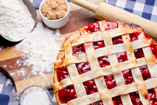 Homemade Cherry Pie on Blue Gingham Checked Tablecloth fresh from the oven with raw ingredients