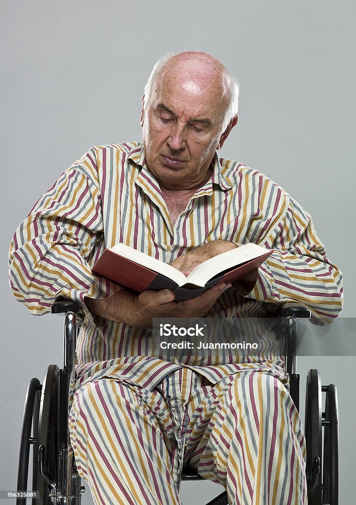 Senior en fauteuil roulant et lire un bon livre - Photo de 65-69 ans libre de droits