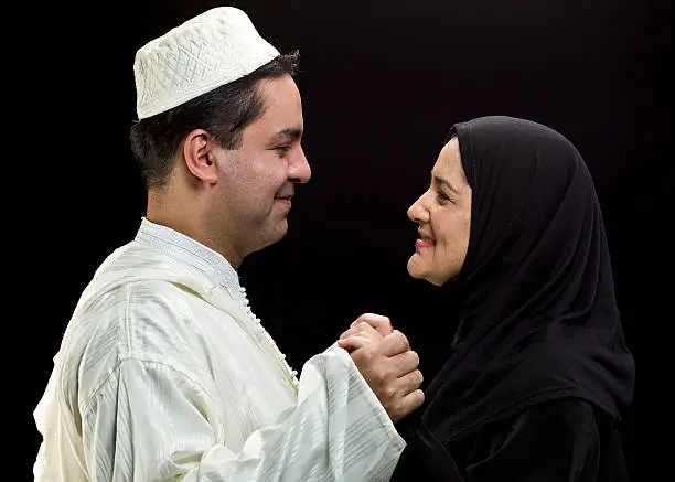 Smiling middle eastern couple holding hands on black background (this picture has been taken with a Hasselblad H3D II 31 megapixels camera) 