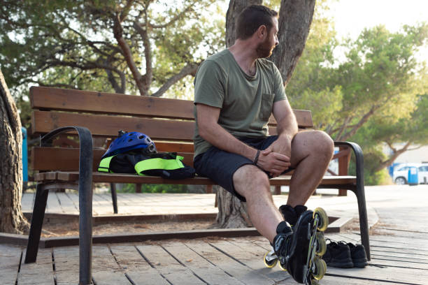 istock Man with inline skates on sitting on a bench while is waiting a friend. 1563254792