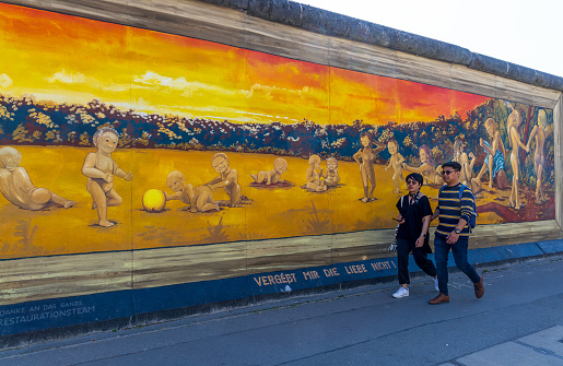 Berlin, Germany - June 1, 2023: Tourists visiting free public urban art of East Side Gallery on a public street in Berlin, Germany