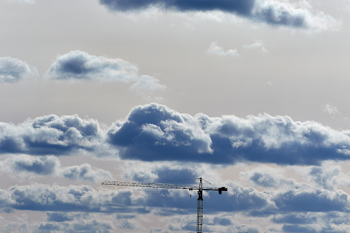 Image tower construction crane on the background of the sky with clouds