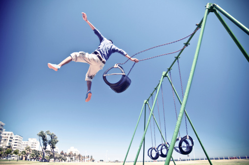 Free Runner performing a big aerial stunt in Cape Town Sea Point park swings. South Africa.