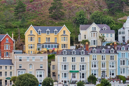 Several colorful townhouses climbing a hill by the beach in Llandudno, Great Britain