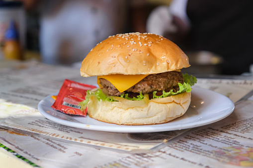 Close-up shot of Cheeseburger with chilli sauce sachet