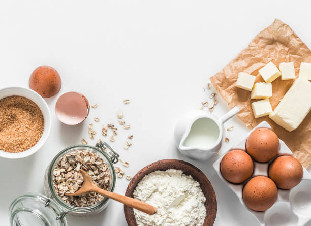 istock Baking ingredients background - oat flakes, flour, cane sugar, butter, eggs on a light background, top view. Copy space 1563293837
