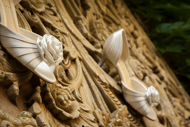 Sapatos de casamento penduradas em uma parede de pedras - foto de acervo