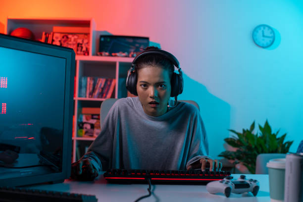 istock Young Asian woman concentrating on playing a video game 1563336899