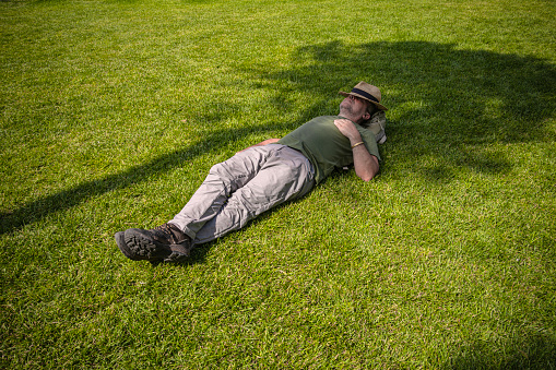 Man in straw hat sleeping in the shade of a tree in hot weather.