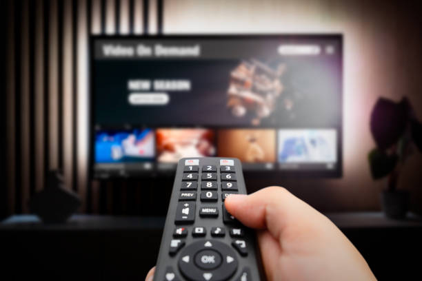 Man watching TV with remote control in hand. VOD service screen. Man watching TV with remote control in hand. ultra high definition television stock pictures, royalty-free photos & images